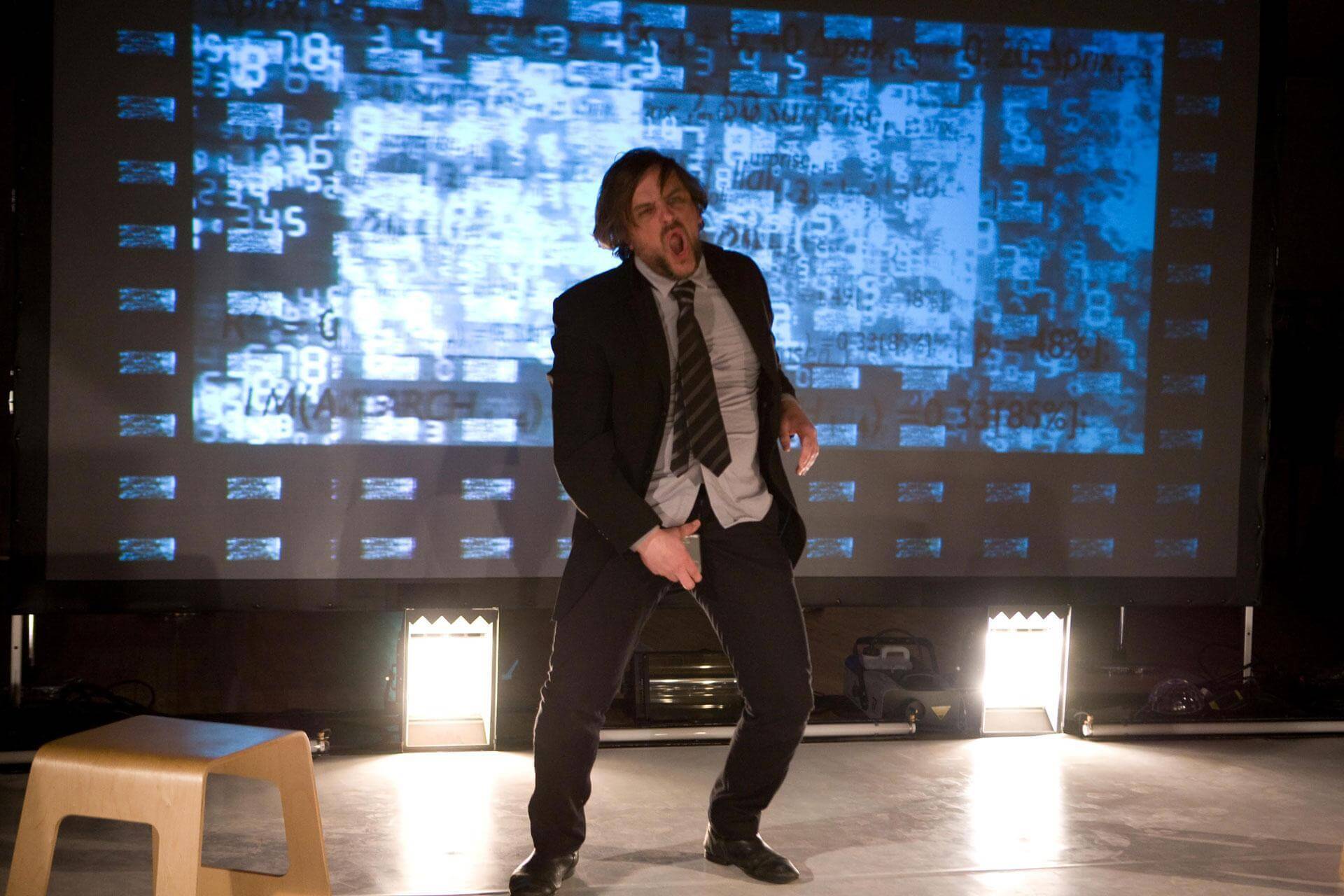 Acteur en mouvement devant une projection de données chiffrées