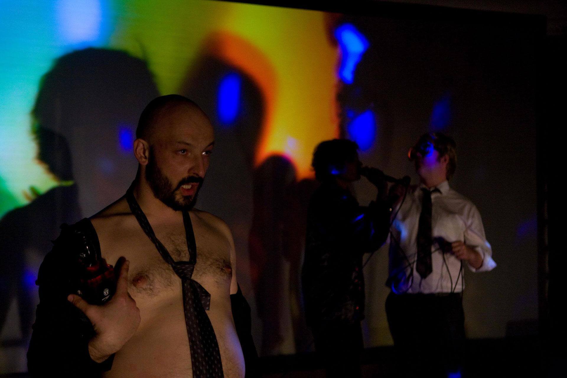 Acteur manipulant une caméra en direct devant une projection colorée
