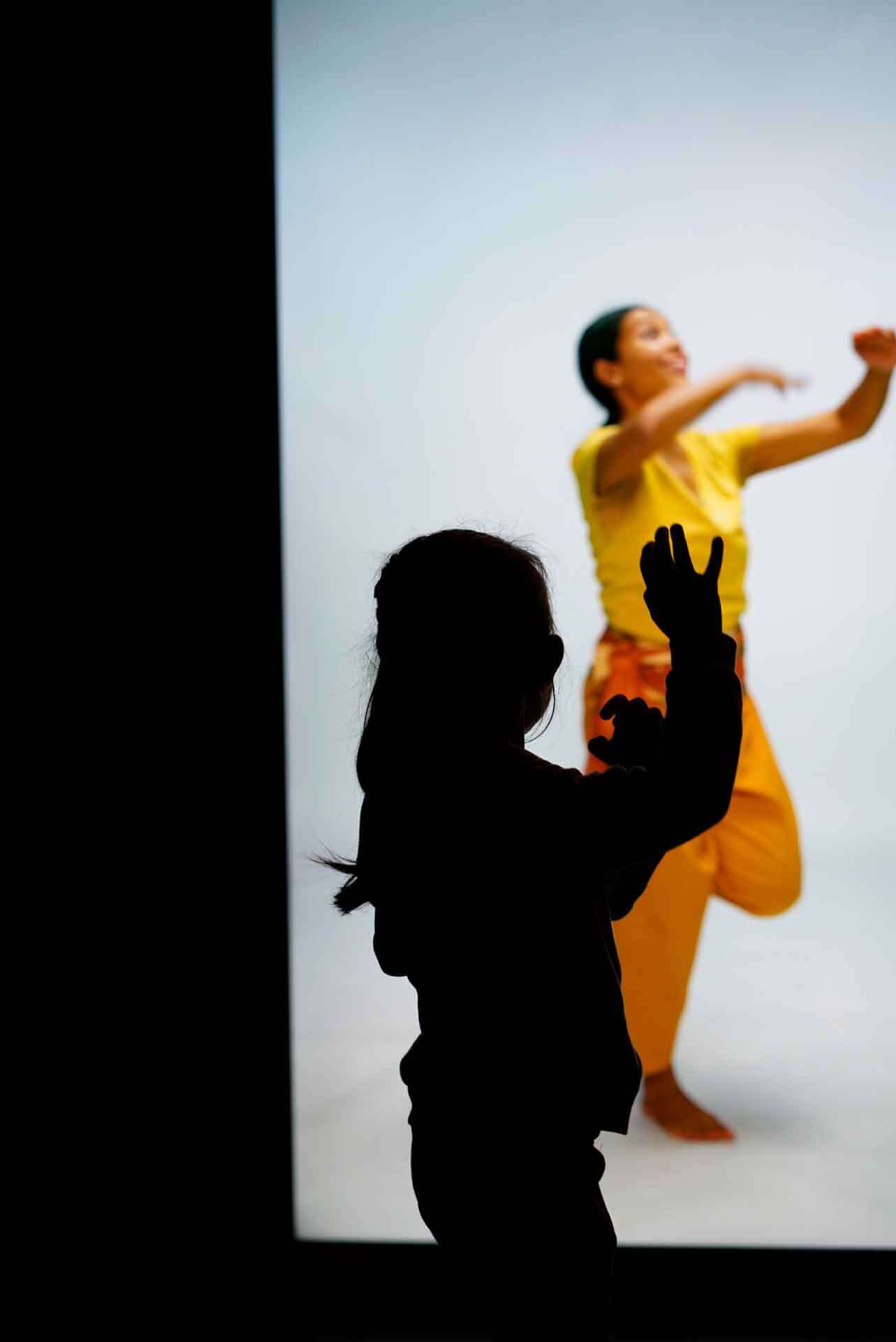 Un enfant danse devant une surface de projection