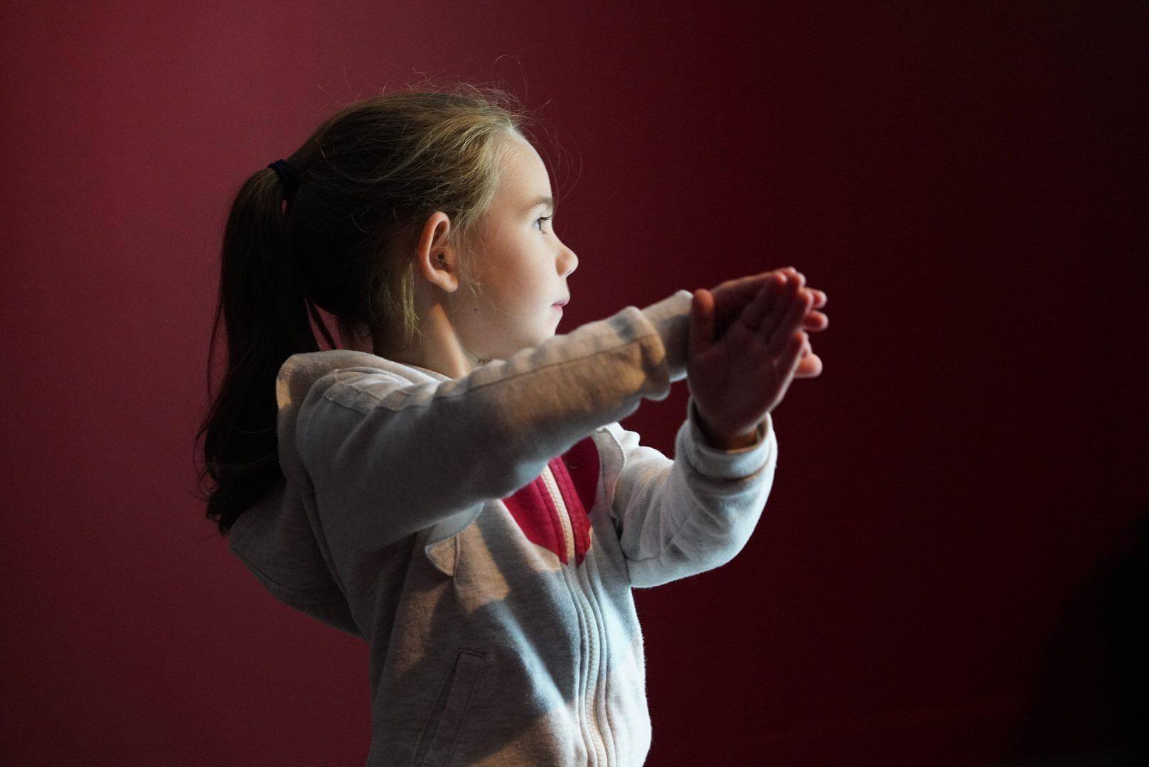 Une enfant, mains jointes, dans la lumière de l'exposition