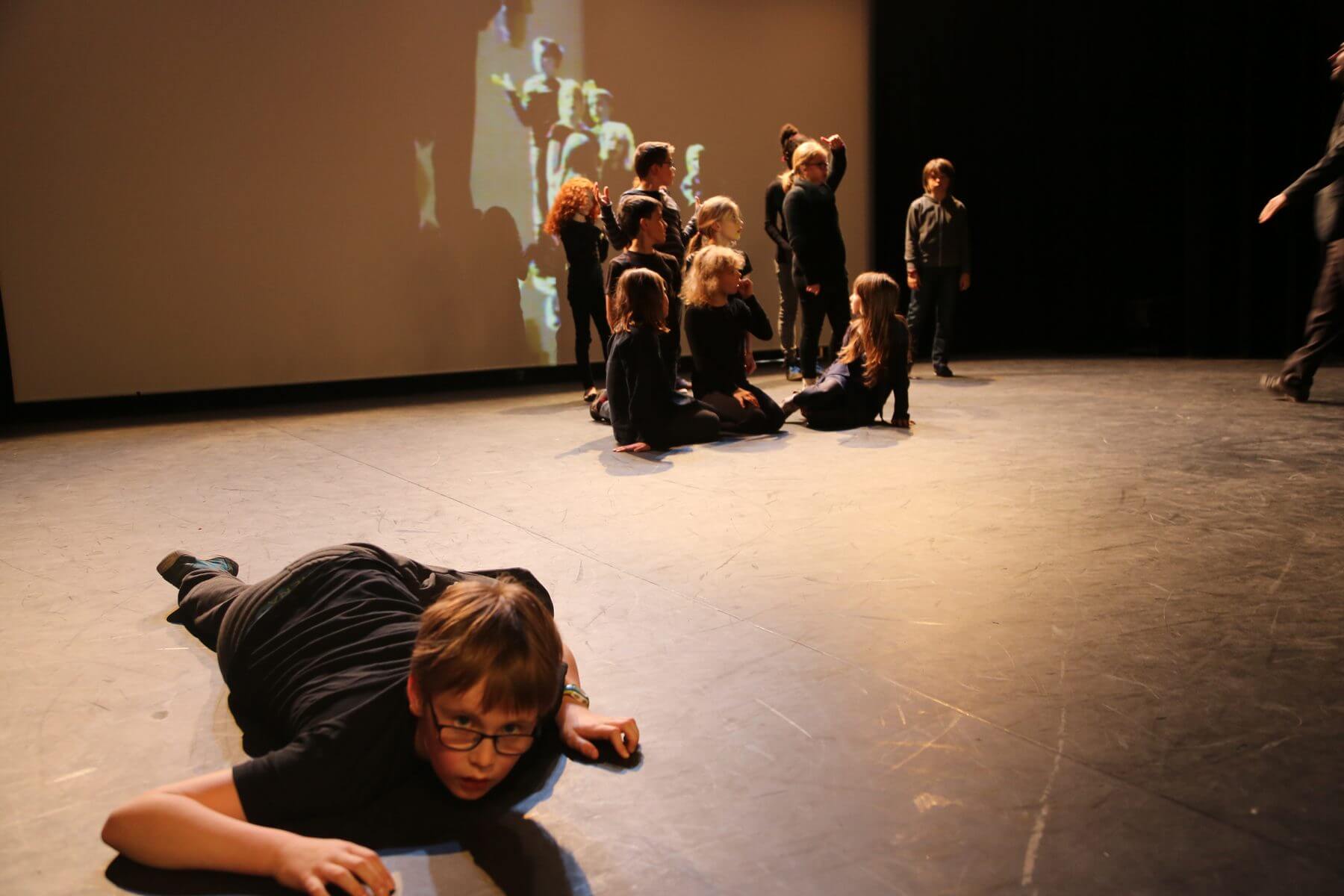 Plateau du Studio Vanacker : un enfant alonge au premier plan, le groupe au fond devant l ecran de projection