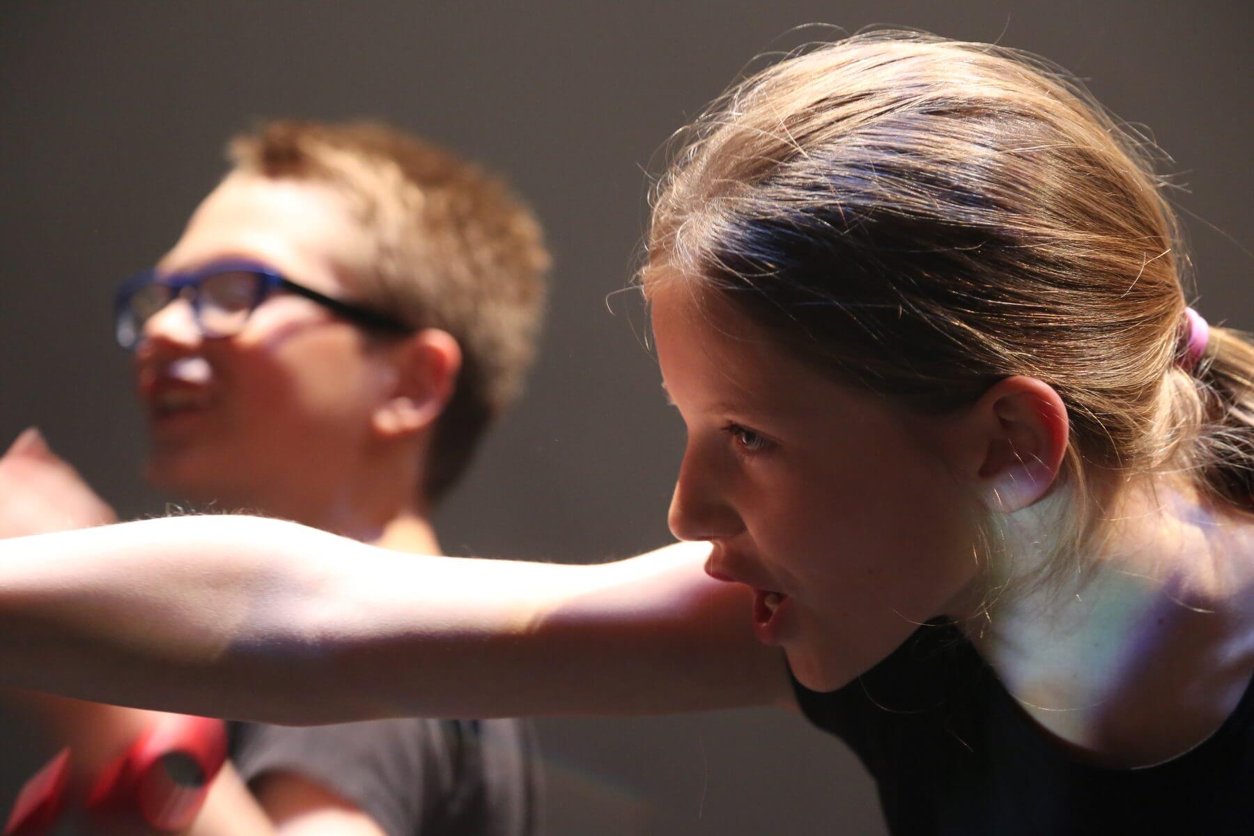 Une enfant bras tendu, en pleine replique, pendant une scene de l atelier