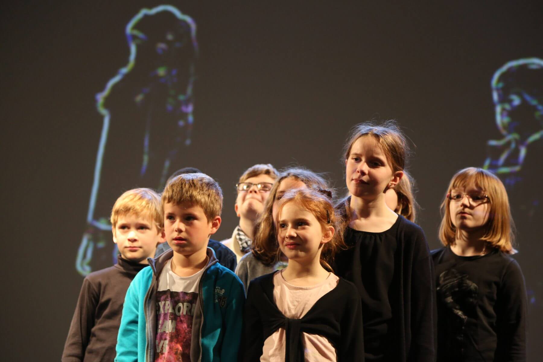 Le groupe mains levees, choeur en mouvement devant la projection video
